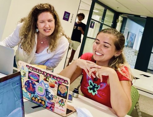 Amy Weinreb and a student smile while studying in front of a laptop