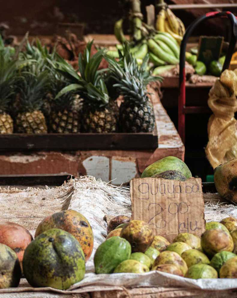 outdoor market displaying various fruit including pineapple and bananas